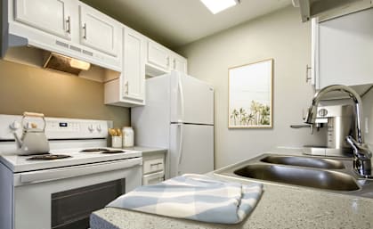 A kitchen with a stove, oven, refrigerator, and sink.