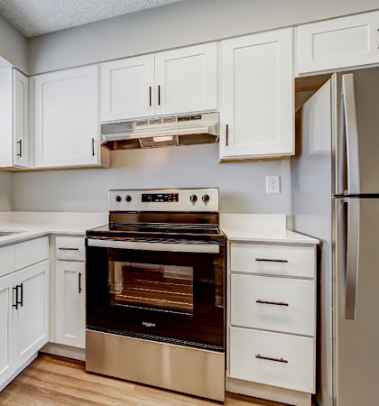 A modern kitchen with white cabinets and stainless steel appliances.