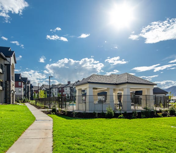 A sunny day in a residential area with a small house in the middle of the grassy area.