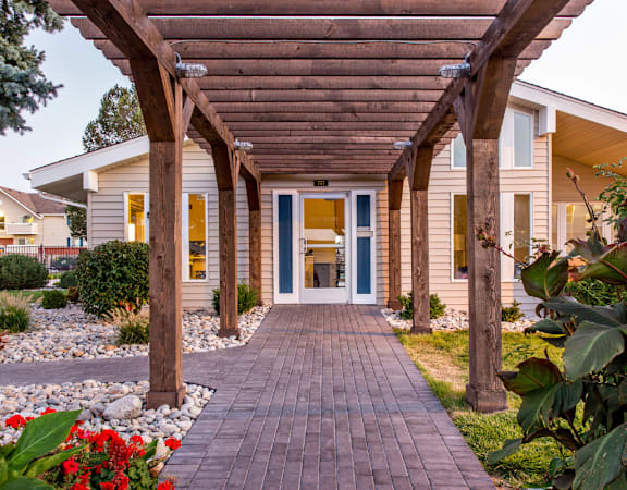 Covered pergola walkway leading to leasing office at Aurora Meadows apartments.