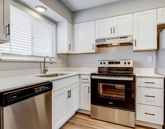 A modern kitchen with white cabinets and stainless steel appliances.