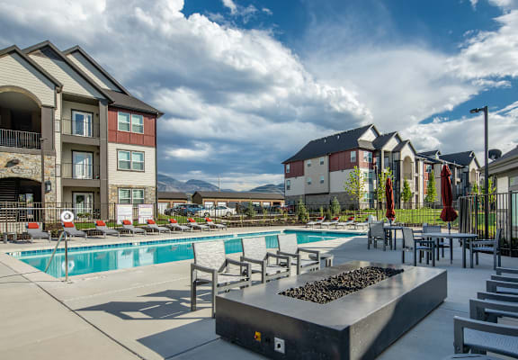 A pool area with a hot tub and lounge chairs in front of apartment buildings.