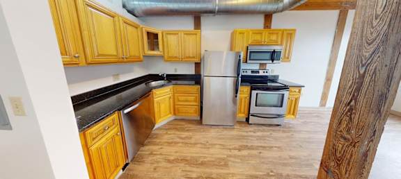 A kitchen with wooden cabinets and a black countertop.