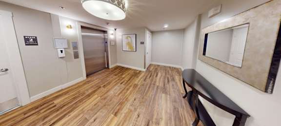 A hallway with a wooden floor and a bench.