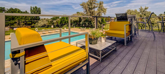 A poolside deck with yellow lounge chairs and a table.