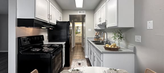 A kitchen with a black stove top oven and white cabinets.