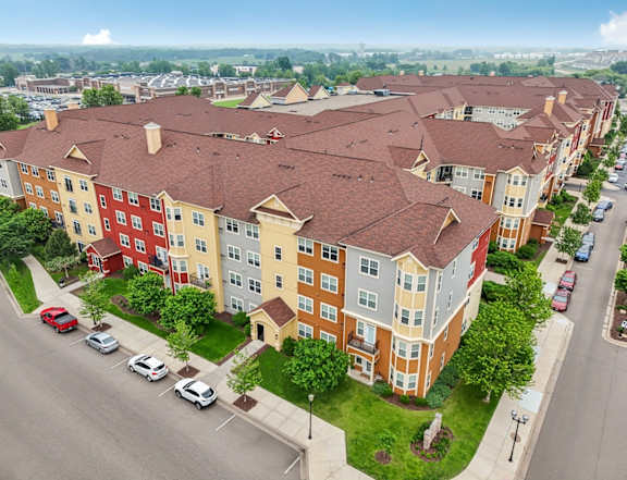 Apartment complex with red roofs and a parking lot in front.