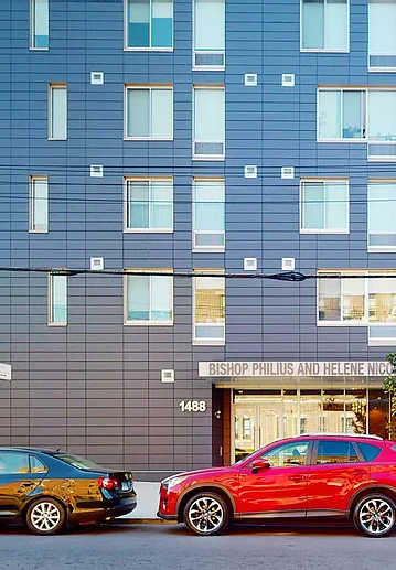 A red car is parked in front of a building with a sign that reads "The Residences at 1111".