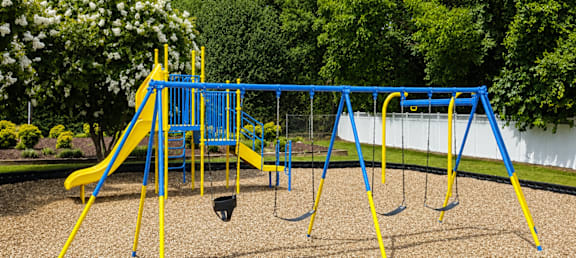A playground with a blue and yellow swing set.