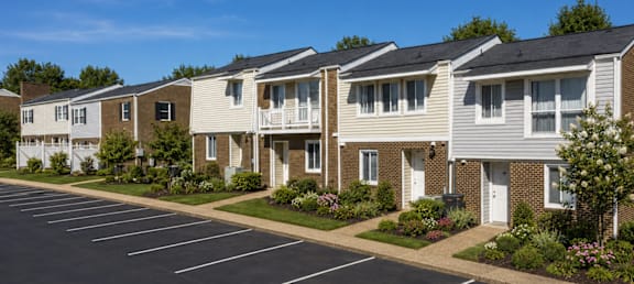 A row of townhouses with a parking lot in front.