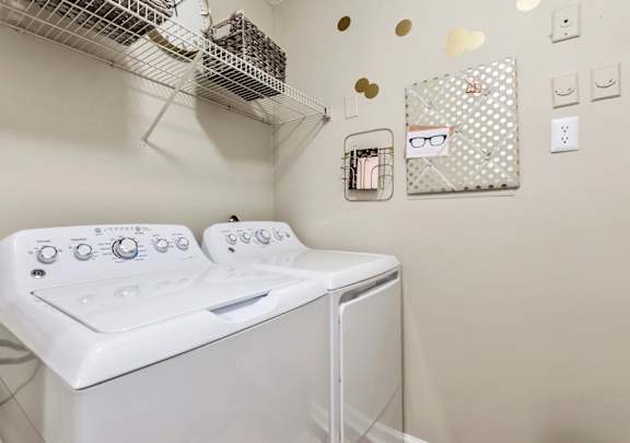 a washer and dryer in a laundry room with a rack on the wall
