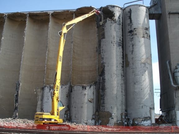 a crane demolishing a concrete silo