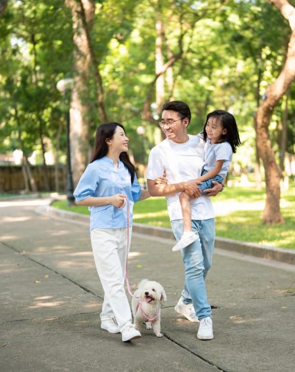a family walking their dog in the park with their child