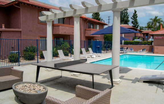 our apartments have a pool and a patio with chairs and tables at Summer Meadows in Riverside, CA