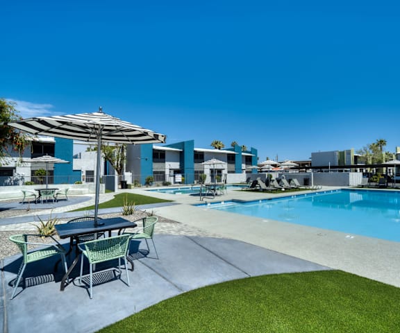 a swimming pool with tables and chairs next to a resort style pool at Connect on Missour Apartments, Phoenix 85015