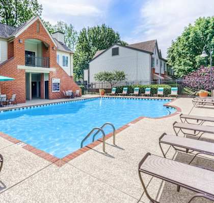 A pool with sun loungers and a building in the background.