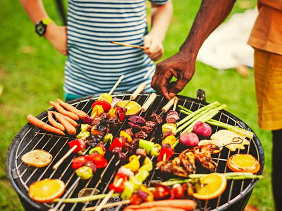 A man is grilling various foods on a barbecue.
