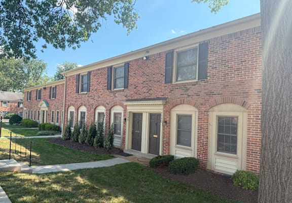 A row of red brick houses with white trim and black shutters.