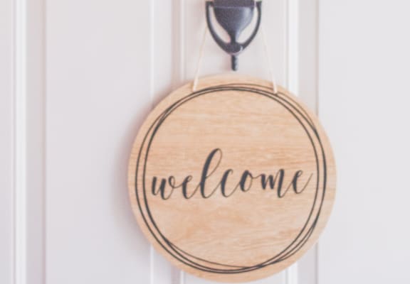 a welcome sign on a door with a wreath and a hoop on the wall