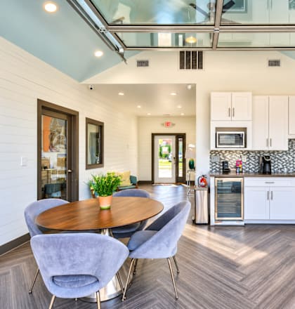 A modern kitchen with a wooden table and grey chairs.