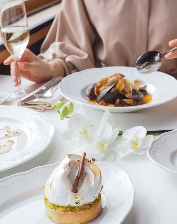 A person is sitting at a table with a dessert in front of them.
