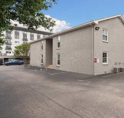 A grey building with a parking lot in front.
