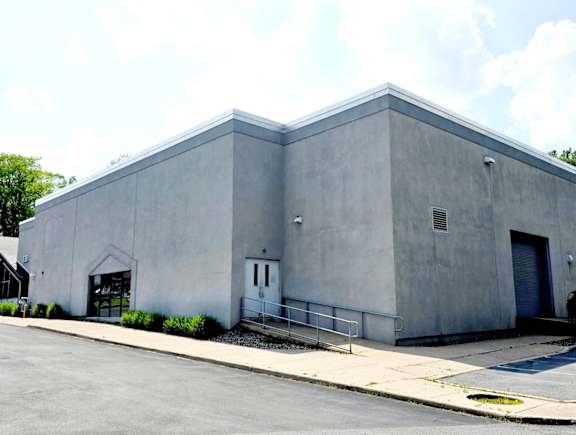 A grey building with a white door and a black gate.