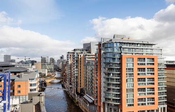 A river flows through a city with modern buildings on either side.at Slate Yard Apartments, Salford