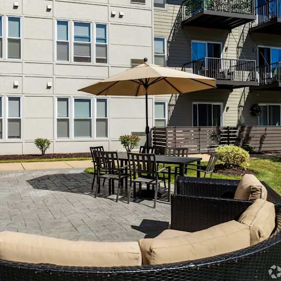 a patio with a grill and tables in front of an apartment building