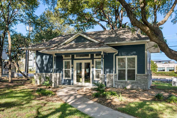 a small house with a sidewalk and trees in front of it at South Lamar Village, Austin, TX