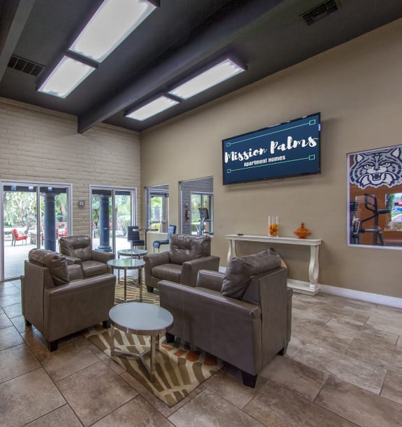 a lobby with couches and chairs and a tv on the wall