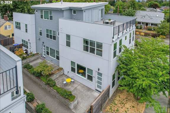 A modern two-story building with a balcony and a small garden in front.