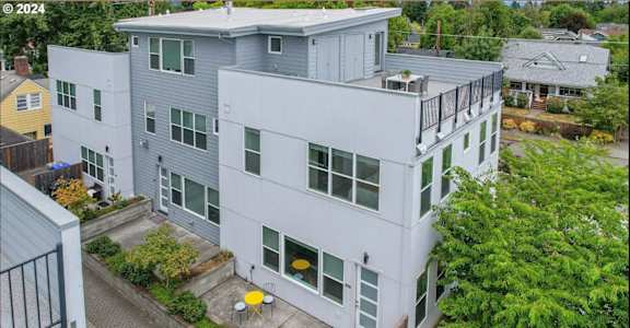 A modern two-story building with a balcony and a small garden in front.