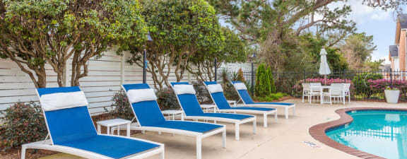 a row of blue and white lounge chairs sit next to a pool