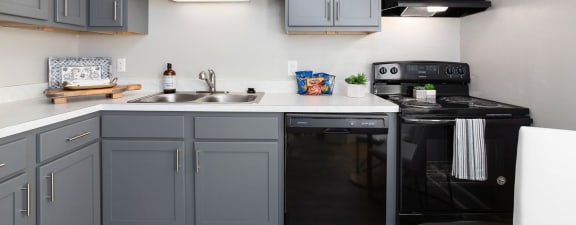 a kitchen with gray cabinets and black appliances