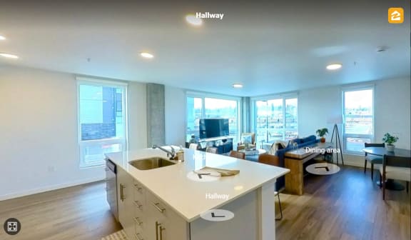 an open kitchen and living room with a couch and a tv