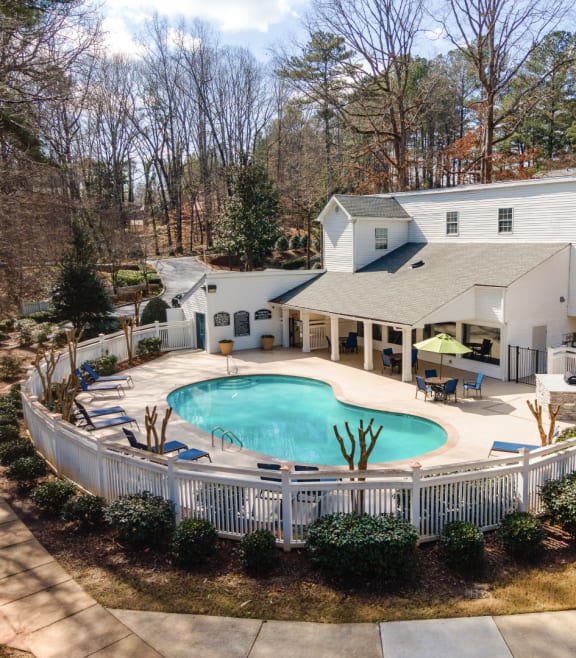 an aerial view of a pool and spa with a white picket fence