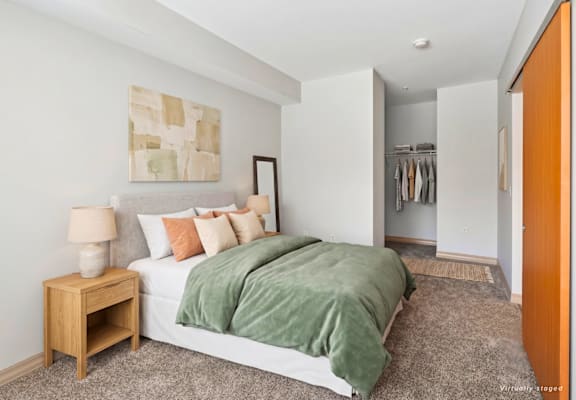 A bedroom with a bed, nightstand, and a painting on the wall.
