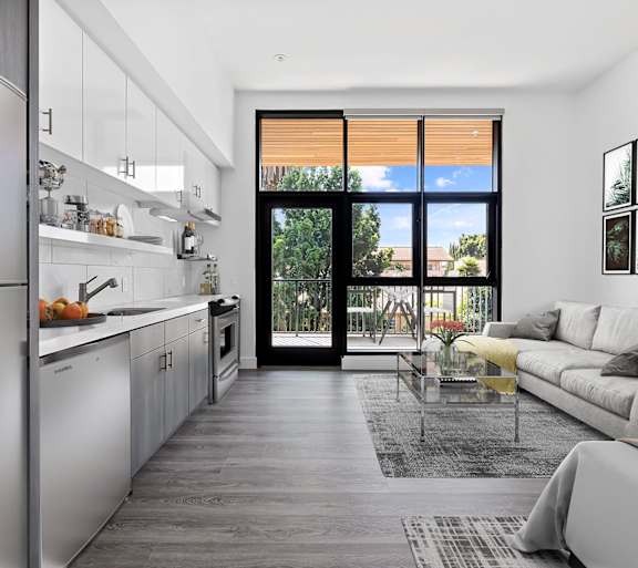 A modern kitchen with a large island and a view of the backyard through the sliding glass doors.