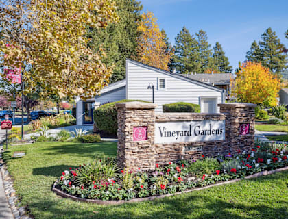 A sign that says Vineyard Gardens in front of a house.