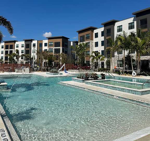 the pool is surrounded by palm trees and plants at The Concord Apartments, Sarasota , FL 34240