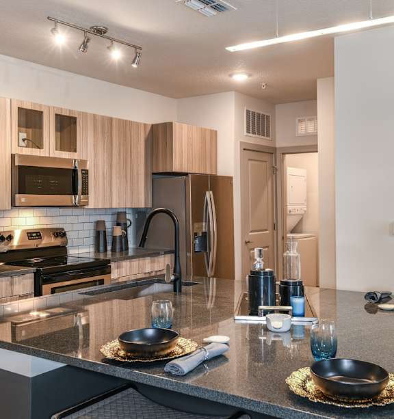A modern kitchen with a granite countertop and stainless steel appliances. at CODA Apartments , Orlando, FL, 32826
