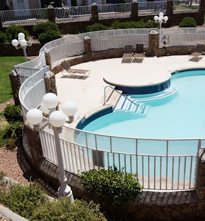an aerial view of a swimming pool with chairs and a fence around it