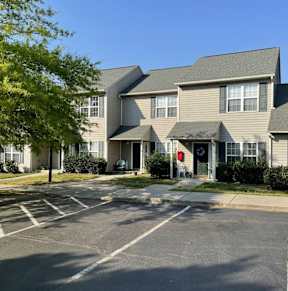 A parking lot in front of a building with a red door.