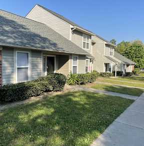 A row of houses with a sidewalk in front.