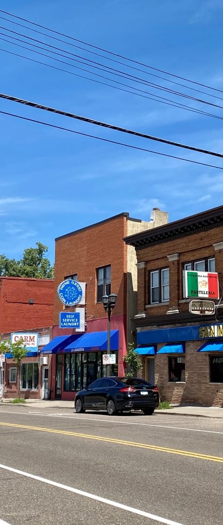 a brick building with blue awnings on a street corner