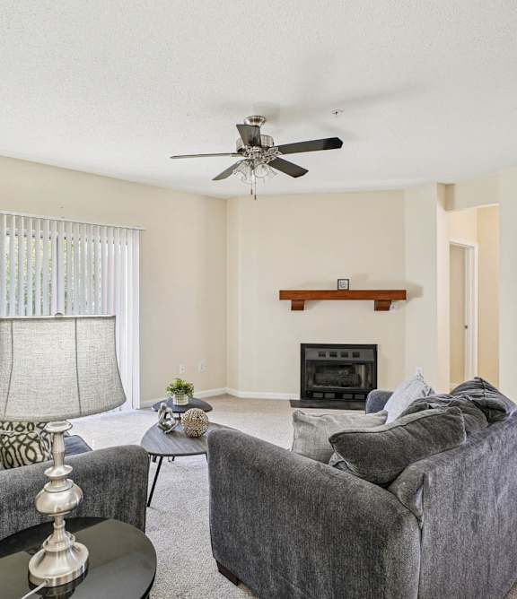 A living room with grey couches and a fireplace.