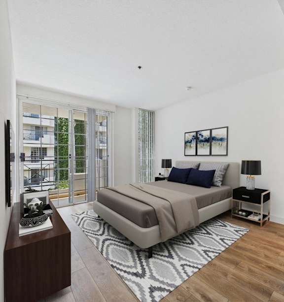 A bedroom with a large bed and a balcony with a view of a building.