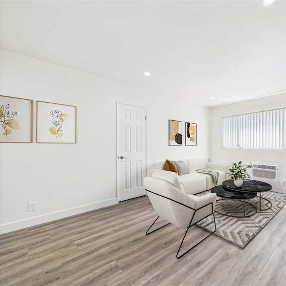A living room with a green couch, a white chair, and a wooden cabinet.