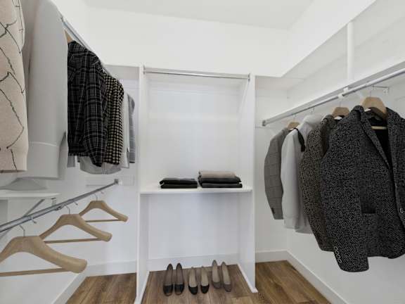 A white closet with clothes and shoes.